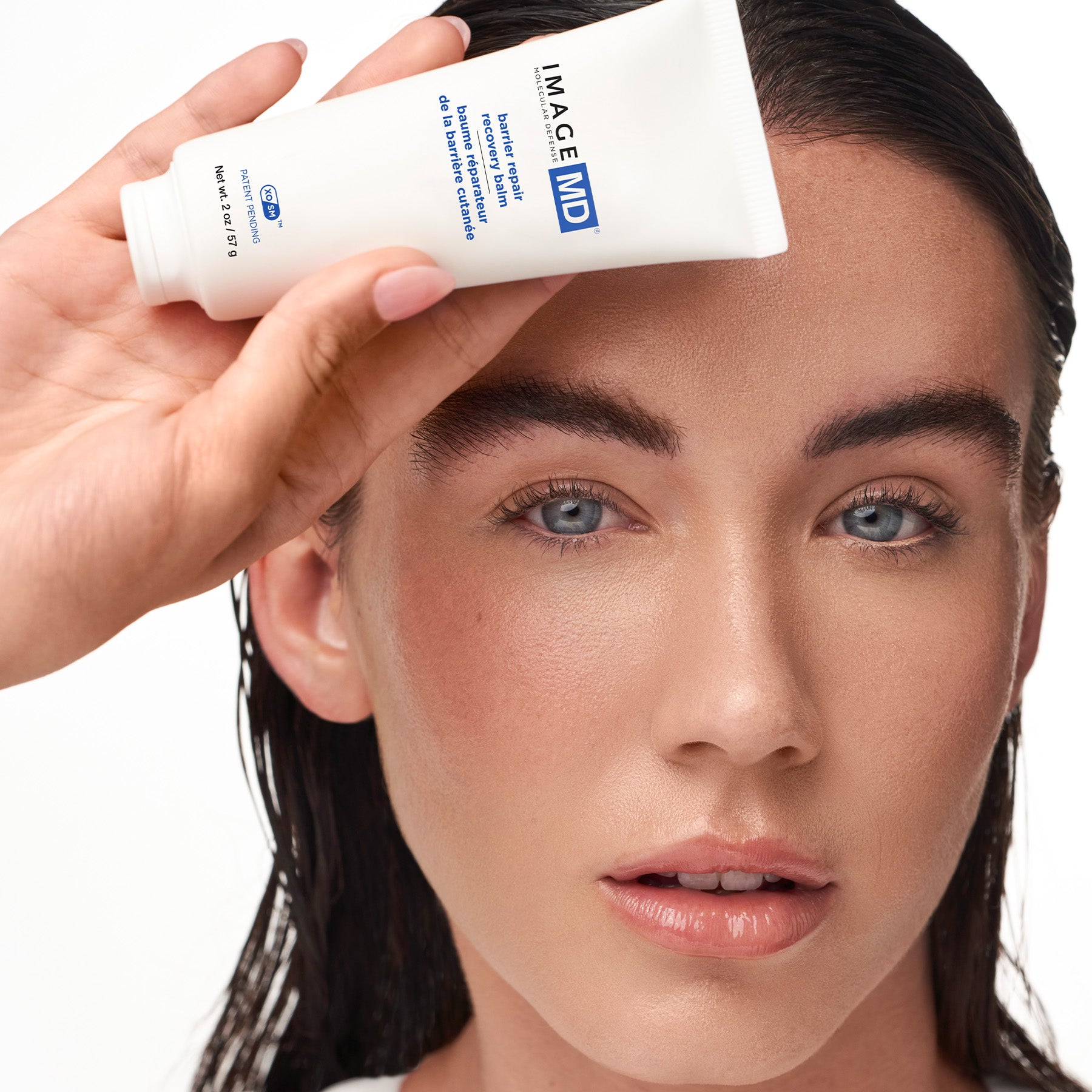 Woman applying skincare product to her face with a focus on the brand 'IMAGE MD'.