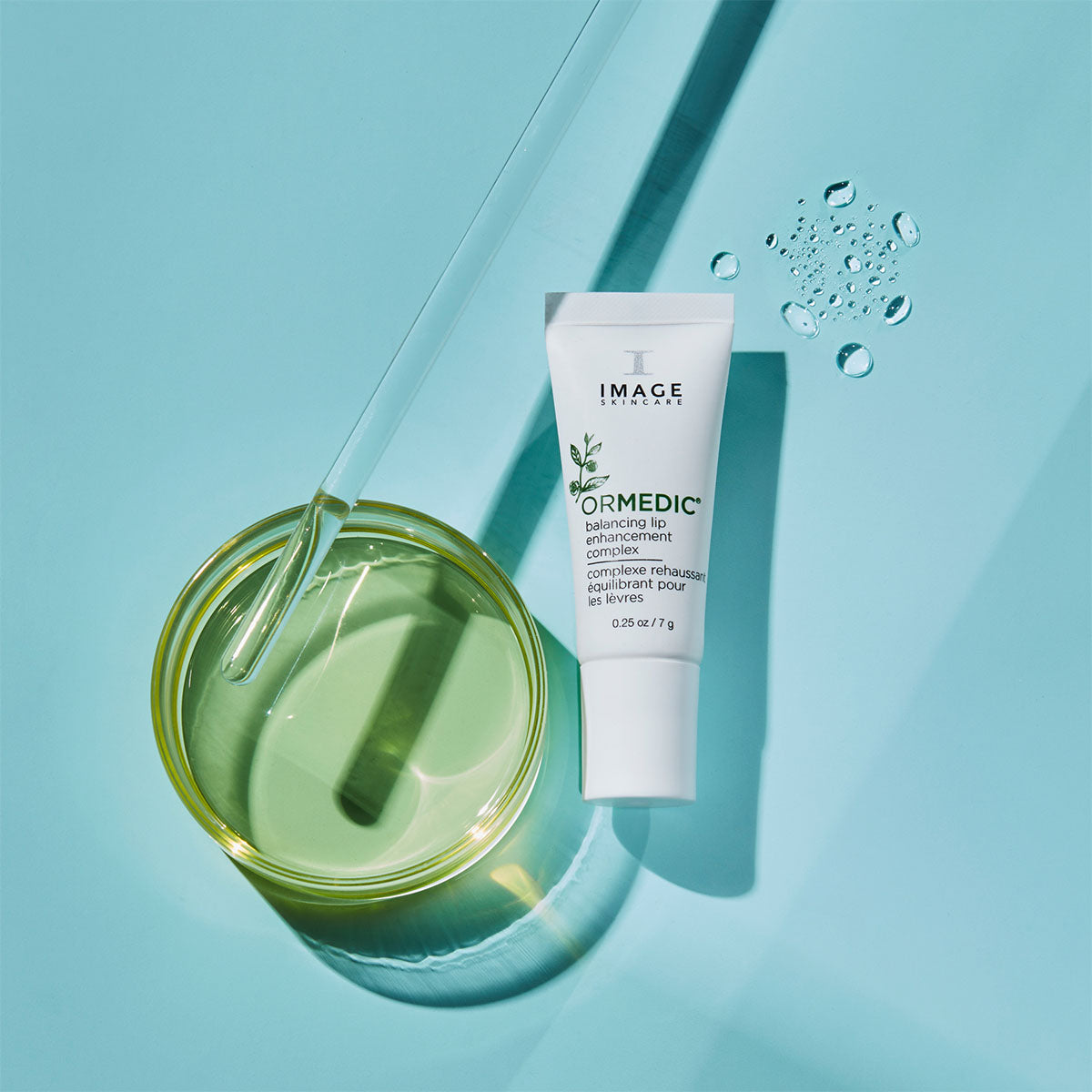 Tube of Image Skincare product on a light blue background with a glass container of green liquid.
