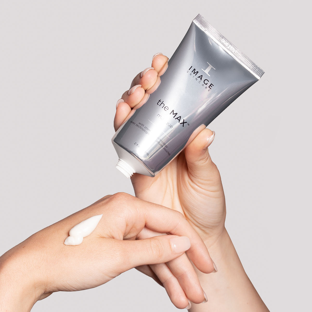 model hands holding max masque tube in one hand and dispensing product into palm