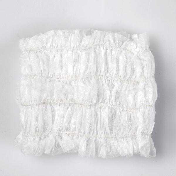 A white disposable headband laid flat on a white surface.