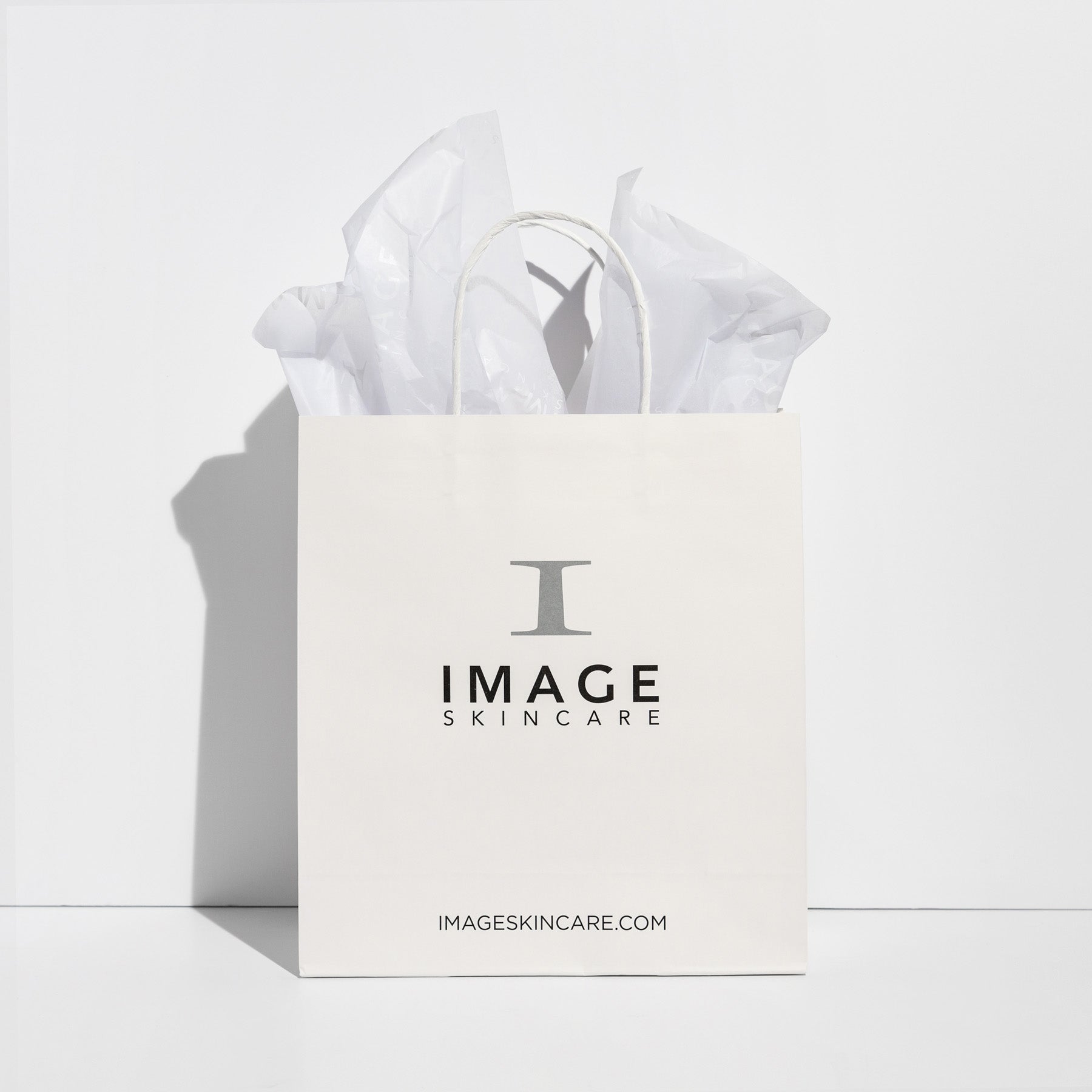 A white tissue paper with the IMAGE Skincare logo printed in black, placed inside a matching white IMAGE Skincare gift bag.