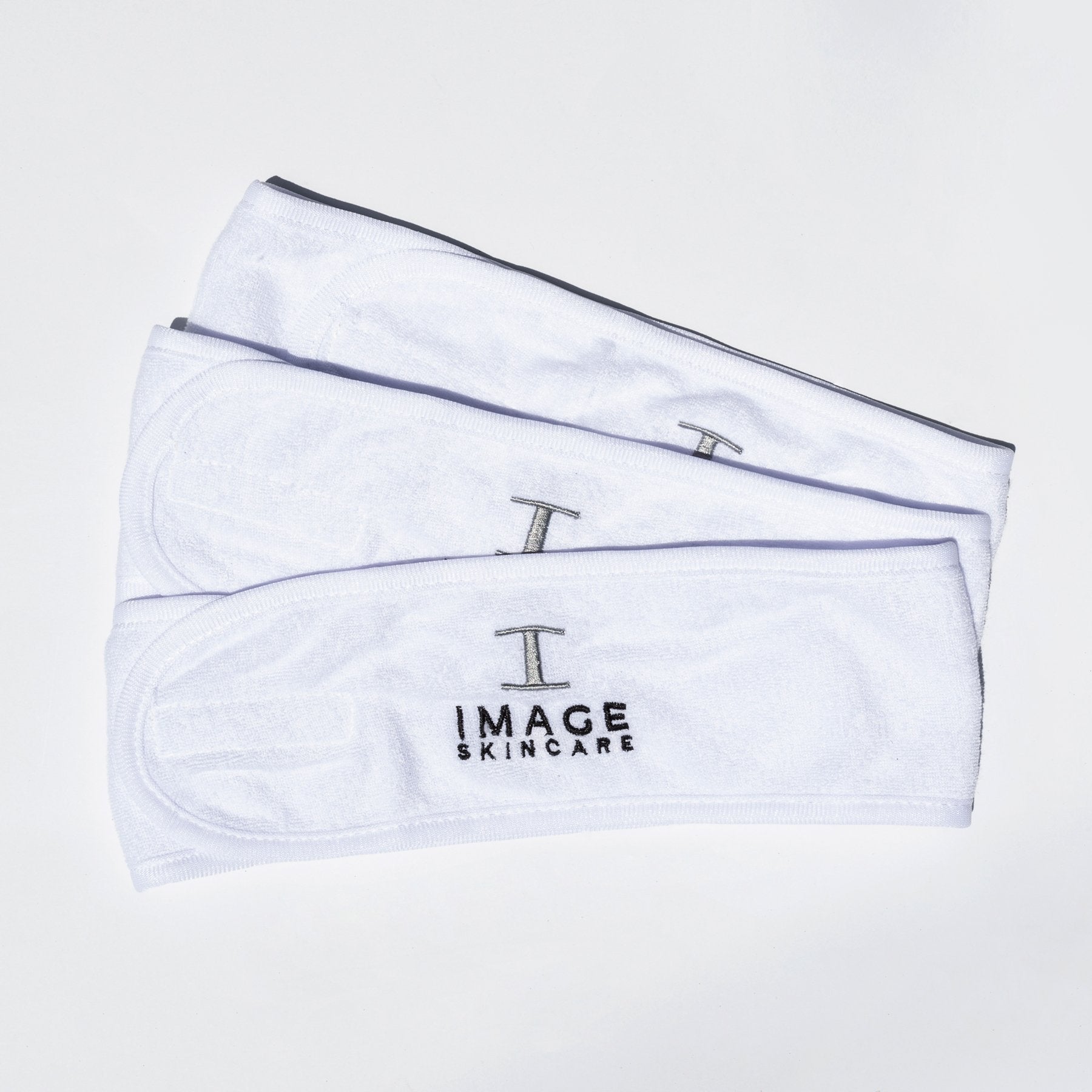Two white terry cloth headbands with the Embroidered IMAGE logo, laid out on a surface.